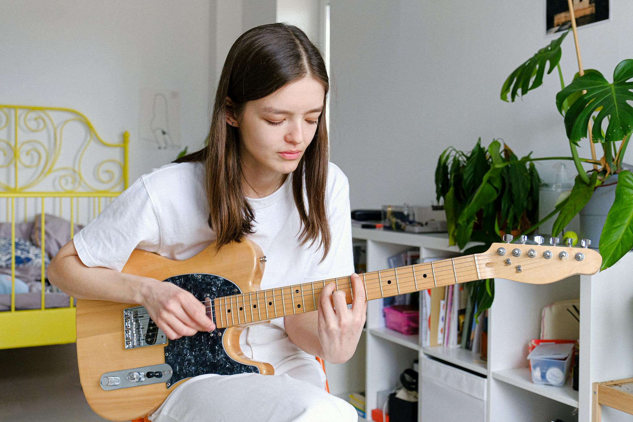 A woman enjoying her hobby of playing electric guitar indoors.